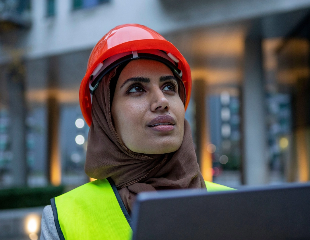 A female construction working wearing a red hard hat