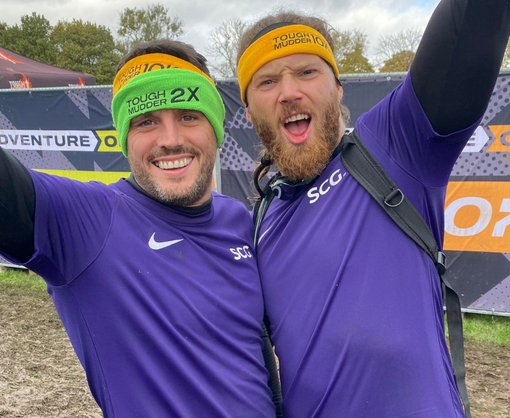Two male Spencer Clarke Group employees celebrating after Tough Mudder