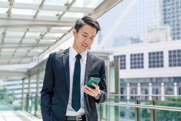 A man wearing a suit looking at a mobile phone in a green case
