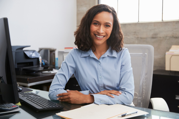A lady wearing a blue shirt sat at a desk smiling