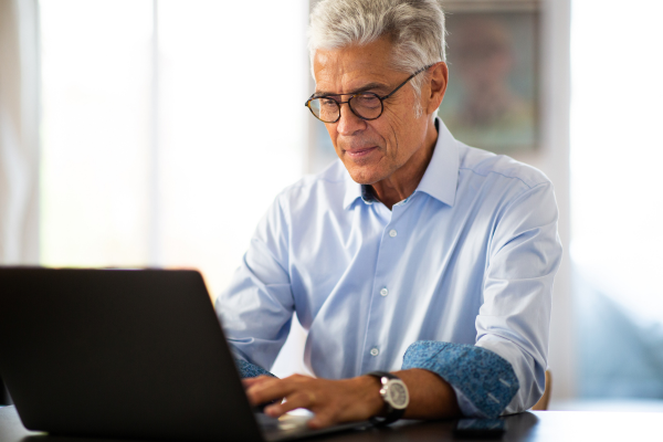 A man wearing a blue shirt working at a laptop