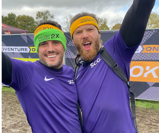 Two male Spencer Clarke Group employees celebrating after completing Tough Mudder